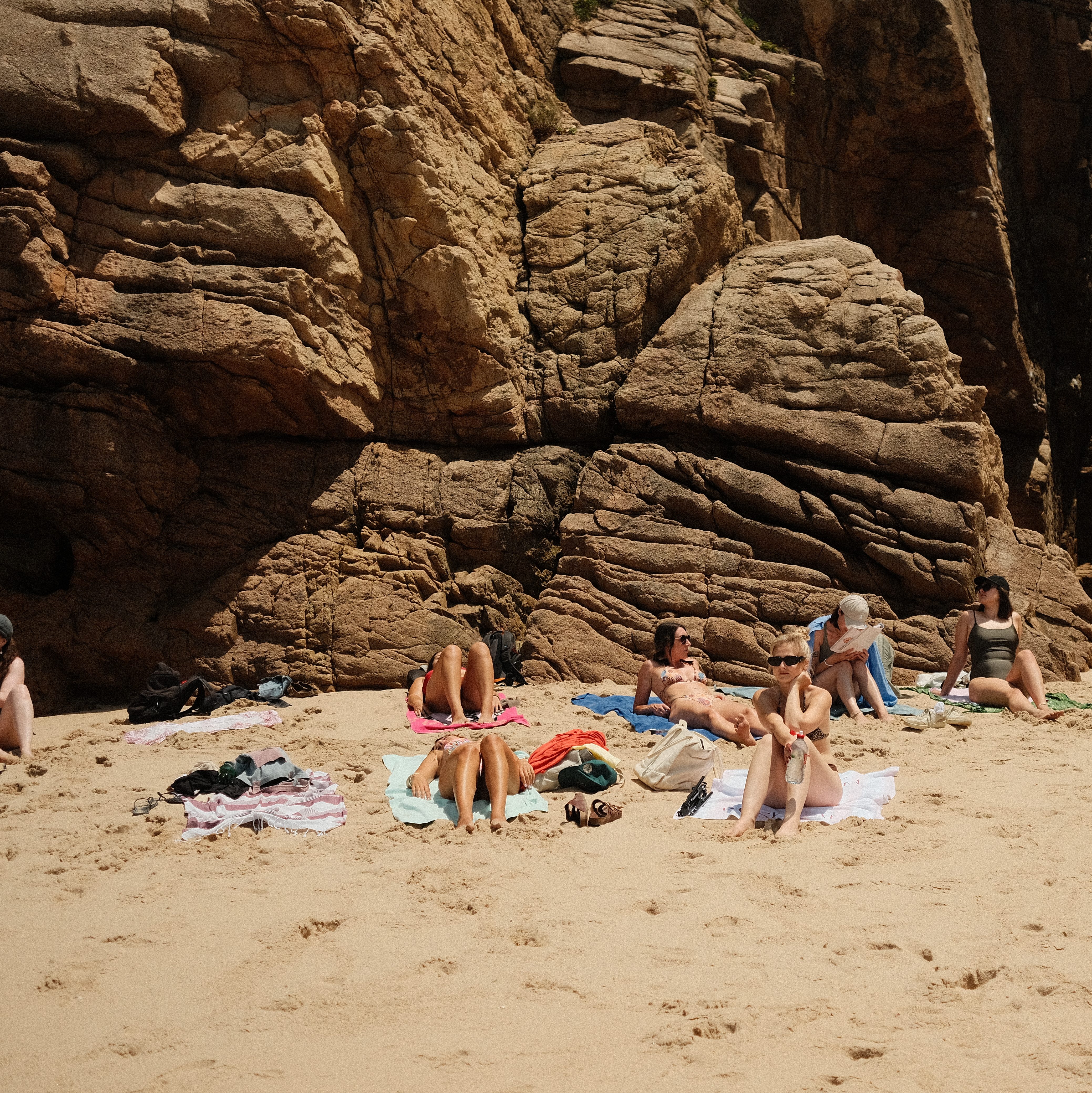 Girls laying out on the beach near the rocks